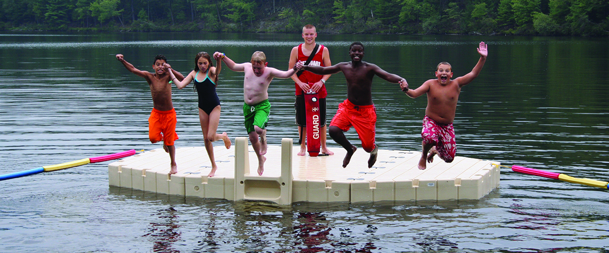 children jumping off dock into water